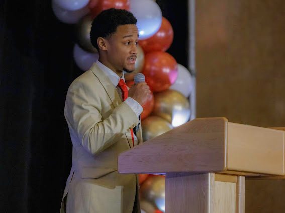 Yohan speaking into a microphone at a podium at the Antonio Johnson Scholarship Gala